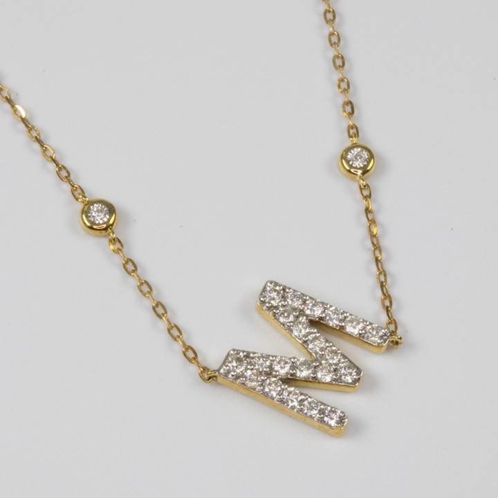 9K Yellow 0.30ct Diamond 'M' Pendant and Chain, 45cm, 1.8g.  Auction Guide: £450-£550