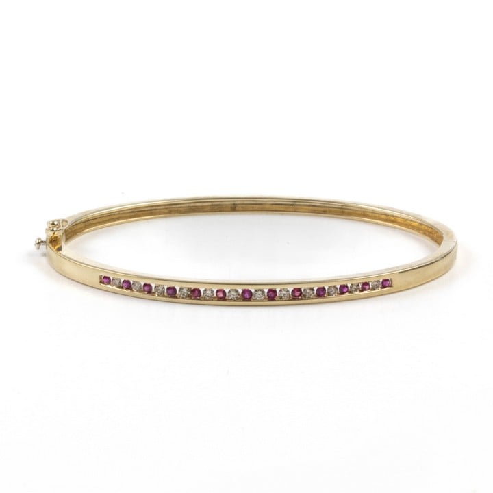 9K Yellow 0.27ct Diamond and Ruby Bangle, 17.5cm, 9.4g.  Auction Guide: £400-£500 (VAT Only Payable on Buyers Premium)