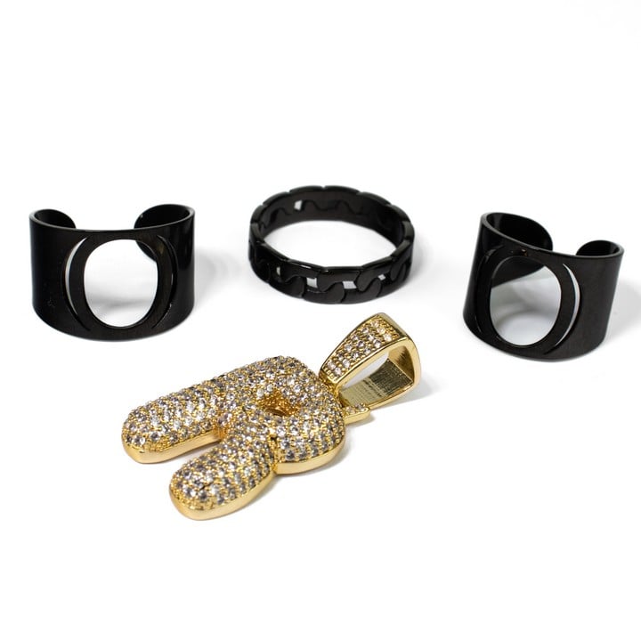 Black metal Pair of Cuff Rings, Black Metal Curb Band Ring, Size U. Gold Plated Metal Clear Stone Pavé Initial 'R' Pendant, 4x1.9cm, total weight 20g (VAT Only Payable on Buyers Premium)