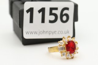 A YELLOW METAL RING SET WITH CLEAR AND RED STONES: LOCATION - CR