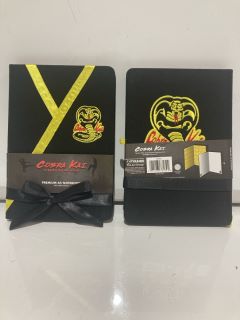 BOX OF ASSORTED ITEMS TO INC COBRA KAI KARATE KID PREMUIUM A5 NOTEBOOK RRP£100